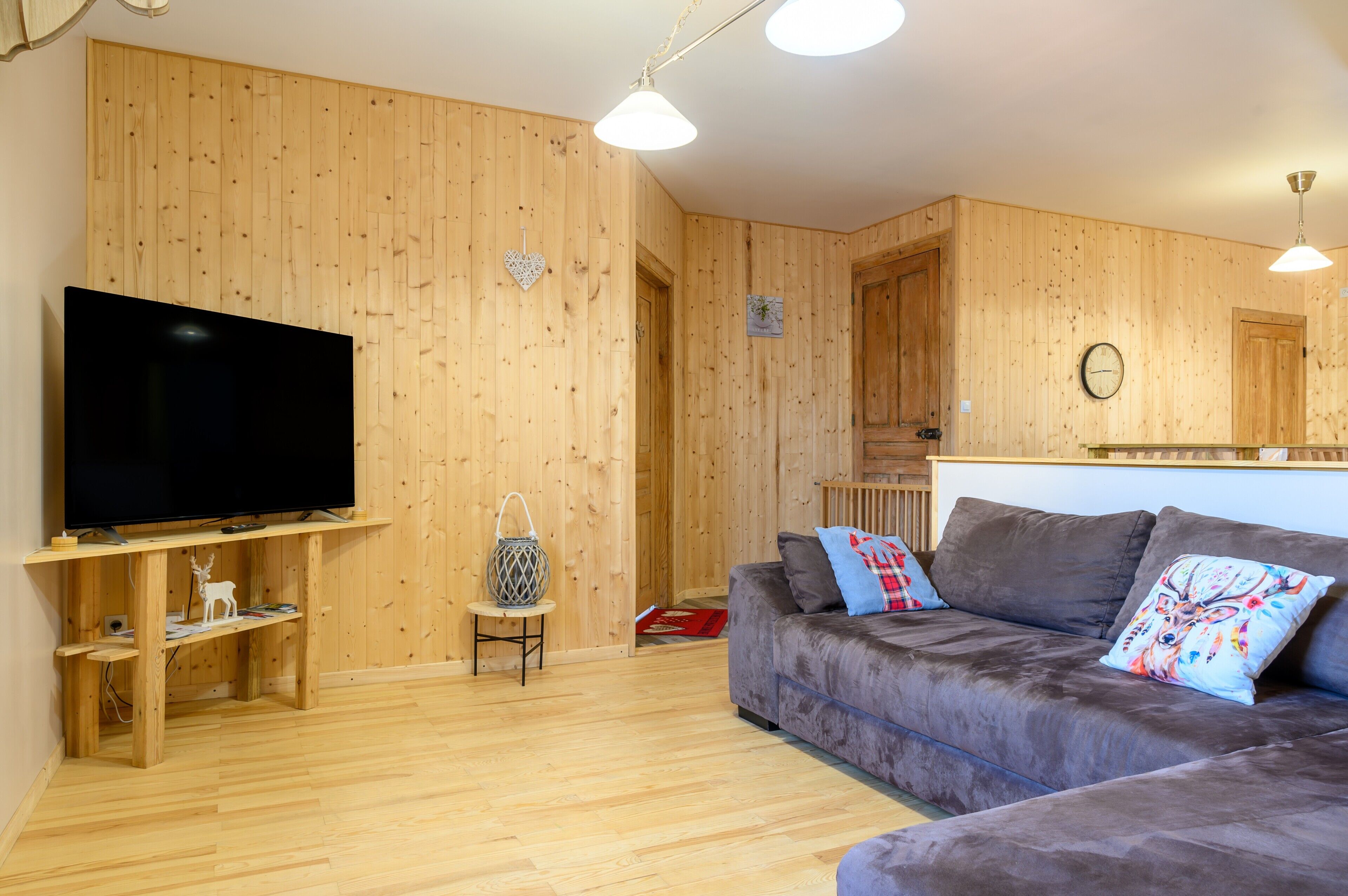 A wooden-paneled room with a flat-screen TV, a sofa, and a small table.