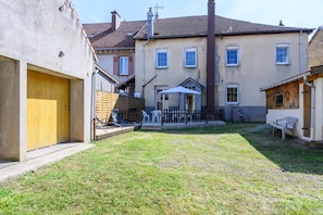 A residential building with a wooden door, a fenced patio, and a small garden area.