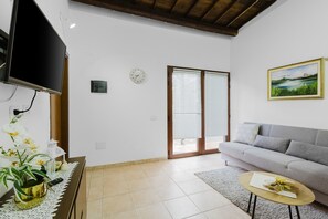 Un salon avec un canapé, une table basse, un téléviseur, une plante et un tableau accroché au mur.