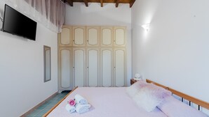 A bedroom with a bed, a TV, a wardrobe, and a bedside table.