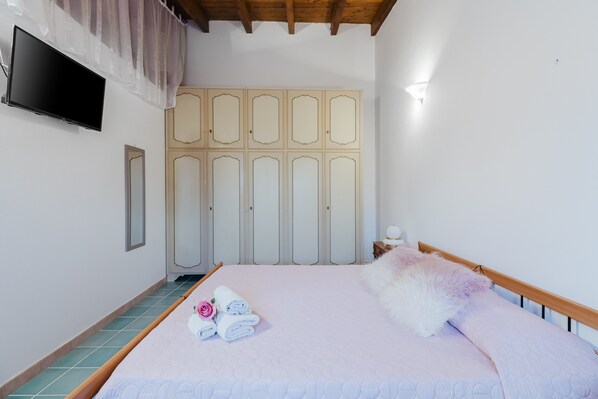 Une chambre à coucher avec un lit, une télévision, une armoire et une table de chevet.