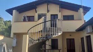 A two-story building with a spiral staircase, a flat roof, and a small balcony.