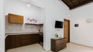 A kitchen with wooden cabinets, a countertop, a stove, and a television mounted on the wall.
