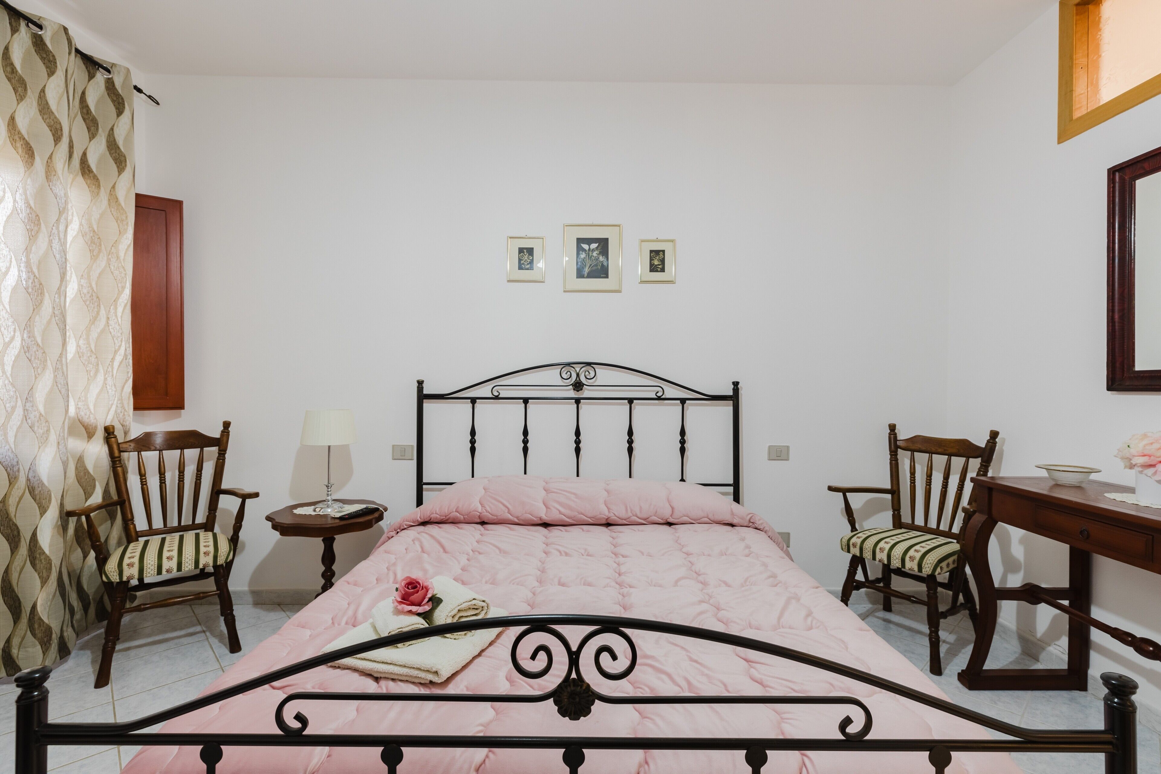 A bedroom with a bed, two chairs, a small table, and a desk.