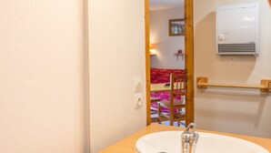 A bathroom with a white sink, a wooden chair, and a towel rack. - Apartment 'Le Jardin Des Neiges' with Balcony (Praz-sur-Arly)