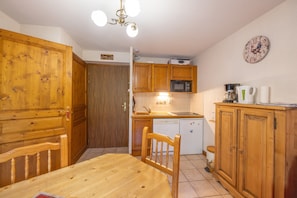 A kitchen with wooden cabinets, a microwave, a sink, and a dining table with chairs.