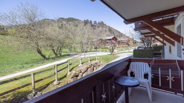 A balcony with a view of a mountain, a wooden fence, and a white chair. - Apartment 'Le Jardin Des Neiges' with Balcony (Praz-sur-Arly)