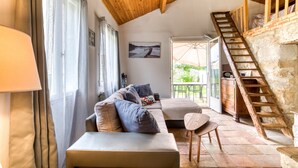 A cozy room with a wooden ceiling, a sofa, a small table, and a staircase leading to an outdoor area. - Cottage 'Maison De Campagne' with Private Terrace, Private Garden and Wi-Fi (GIGNAC)