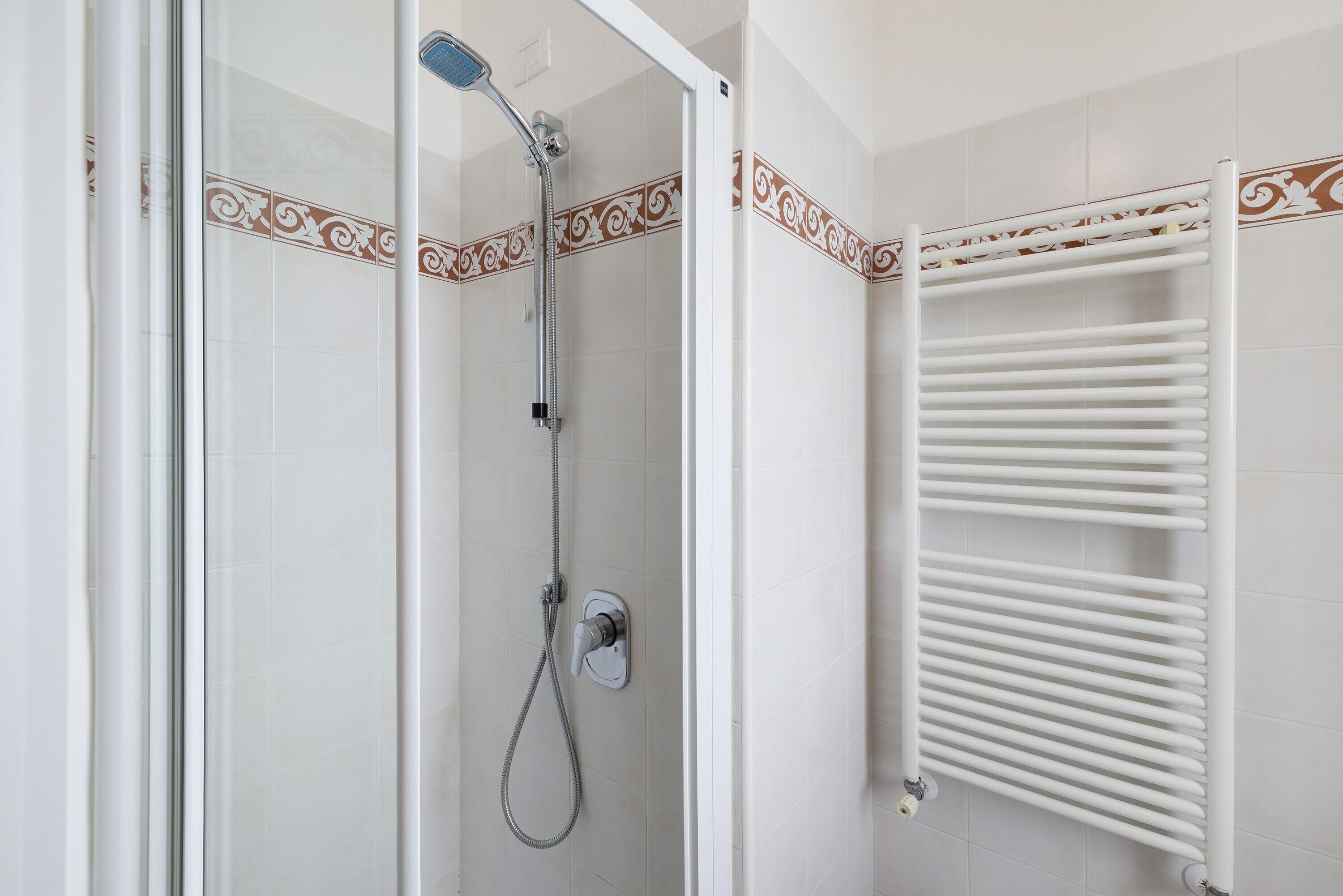 A shower with a handheld showerhead and a wall-mounted control panel.