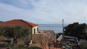 A coastal building with a red-tiled roof, a balcony, and a view of the sea. - Apartment 'La Realidad 3' with Shared Pool, Wi-Fi and Air Conditioning (Finale Ligure)