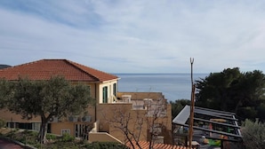A coastal building with a red-tiled roof, a balcony, and a view of the sea. - Apartment 'La Realidad 5' with Shared Pool, Wi-Fi and Air Conditioning (Finale Ligure)