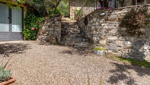 Una escalera de piedra que lleva a un edificio, rodeado de vegetación y un sendero de grava.