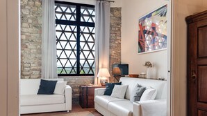 A living room with two white sofas, a stone wall, a window with a lattice design, a lamp, and a painting on the wall. - Apartment 'Fienile' with Private Terrace, Wi-Fi and Air Conditioning (Pelago)