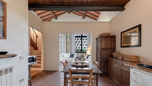 A kitchen with a dining table, chairs, a wooden cabinet, and a view to a living area. - Apartment 'Fienile' with Private Terrace, Wi-Fi and Air Conditioning (Pelago)