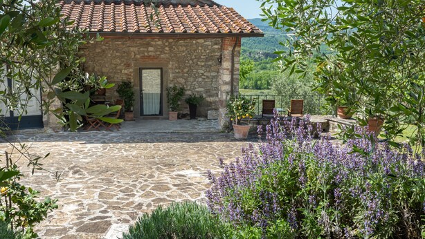 A stone building with a tiled roof, a stone-paved courtyard, and surrounding greenery. - Apartment 'Fienile' with Private Terrace, Wi-Fi and Air Conditioning (Pelago)