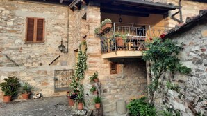 A stone building with a balcony, potted plants, and a small garden area. - Apartment 'Fienile' with Private Terrace, Wi-Fi and Air Conditioning (Pelago)