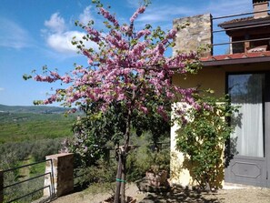 Um edifício com fachada de pedra, varanda e vista para o campo.