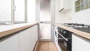 Una cocina compacta con lavadora, estufa y una puerta que da a otra habitación.