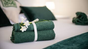 Una cama bien hecha con toallas verdes y una flor blanca.