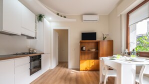 A modern kitchen with white cabinetry, a wooden countertop, and a dining area with a white table and chairs. - Holiday Home 'Sa Mariposa' with Balcony, Wi-Fi and Air Conditioning (Cagliari)