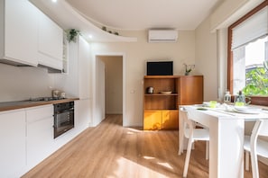 A modern kitchen with white cabinetry, a wooden countertop, and a dining area with a white table and chairs.
