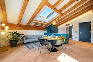 A modern interior with a skylight, wooden beams, a dining area, and a kitchen.