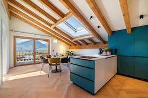A modern kitchen with a skylight, wooden beams, and a view of mountains.