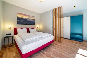 Een moderne hotelkamer met een groot bed, een schilderij aan de muur en een blauwe deur.