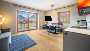 A modern kitchen with a large island, a dining area with chairs, and a view of mountains through large sliding doors. - Apartment 'Villa Rosa Unterschöberlehof - Anna' with Mountain View, Wi-Fi and Air Conditioning (Meran)