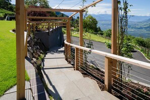 A wooden staircase leading to a covered area with a view of a road and mountains.