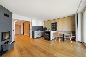 A modern kitchen with wooden flooring, a built-in island, and a dining area with chairs.