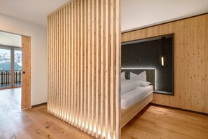 Un dormitorio moderno con cama, paneles de madera y un ventanal grande.