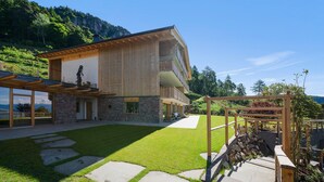 A modern house with a stone facade, a wooden deck, and a view of a mountainous landscape.