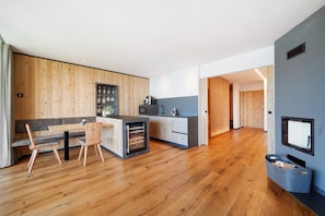 Eine moderne Küche mit Holzelementen, ein Essbereich mit einer Bank und einem integrierten Weinkühlschrank.