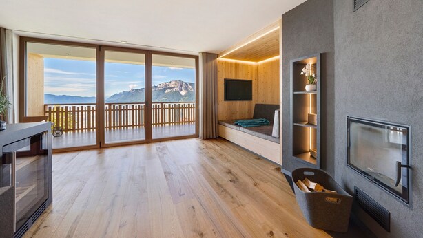 A modern living room with a large sliding glass door leading to a balcony, a flat-screen TV mounted on the wall, and a built-in bench with shelves. - ‘Lodge Melisse’ holiday flat with mountain views, private terrace and private sauna (Mölten)