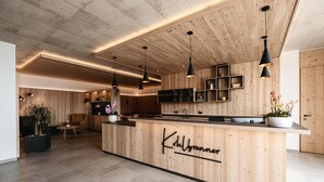 A modern kitchen with wooden cabinetry, a central island, pendant lighting, and a visible name sign. - ‘Lodge Melisse’ holiday flat with mountain views, private terrace and private sauna (Mölten)