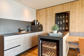Una cocina moderna con un refrigerador para vinos, electrodomésticos integrados y una pared decorativa de madera.