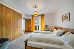 Una camera d'albergo con due letti, un armadio in legno, una scrivania con una sedia e un quadro appeso al muro.