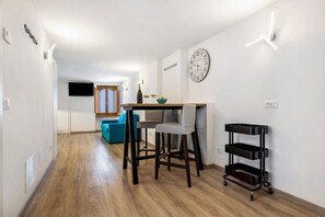Una cocina moderna con comedor, piso de madera, un reloj y un carrito negro.