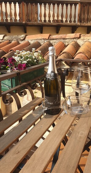 A patio table with a bottle of Casa Cava wine, a glass, and a flower arrangement. - Studio Apartment 'Casa Ciarii 1' with Mountain View, Balcony and Wi-Fi (Tremosine sul Garda)