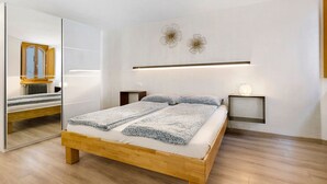 Un dormitorio con cama de madera, un espejo, mesitas de noche e iluminación en la pared.