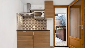 Una cocina pequeña con microondas, armarios de madera y un salpicadero estampado.