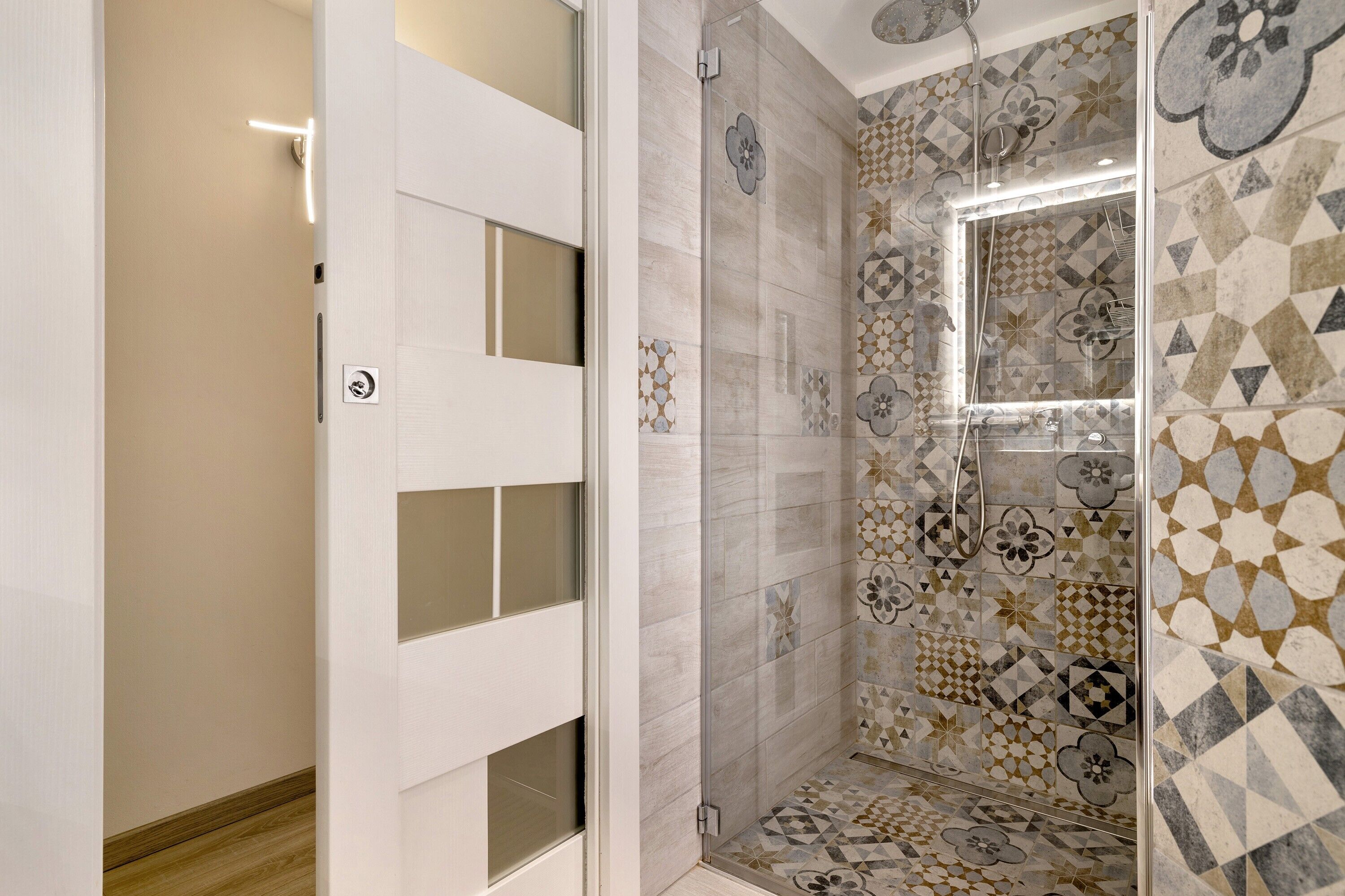 A bathroom with a shower, tiled walls, and a door with frosted glass panels.