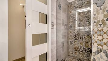 A bathroom with a shower, tiled walls, and a door with frosted glass panels.
