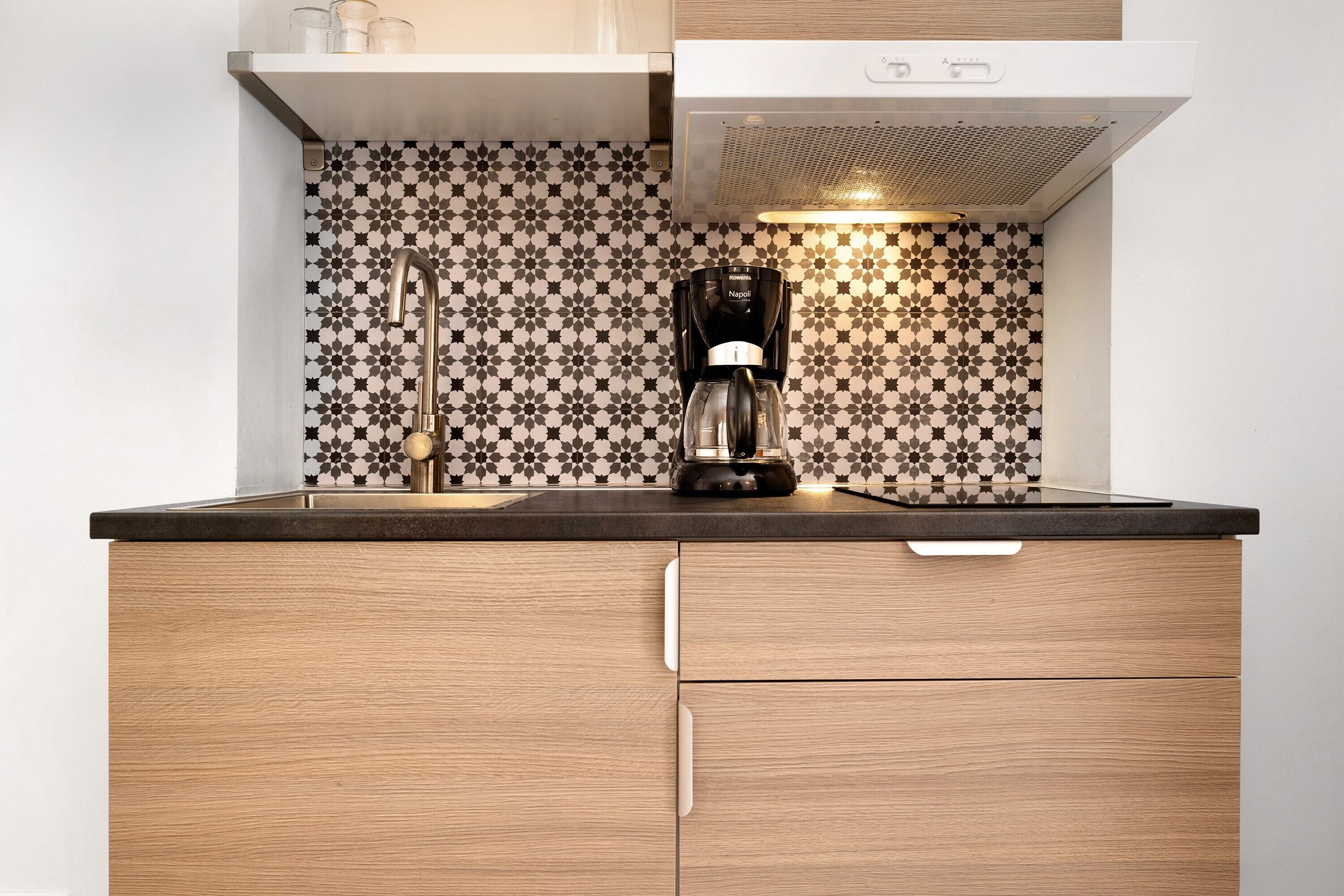 Una cucina con una macchina da caffè, un lavello e uno schienale decorato.