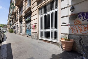 A narrow urban street with buildings, a parked car, and a potted plant. - Apartment 'Porta Venezia Small House' with Wi-Fi and Air Conditioning (milano)