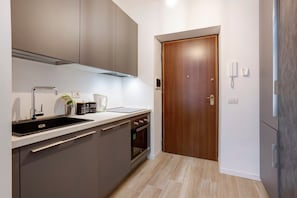 Une cuisine de taille réduite, équipée d’un évier, d’une cuisinière et de placards.