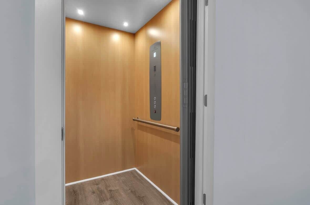 Un ascenseur moderne avec un intérieur en bois et un panneau de commande métallique.