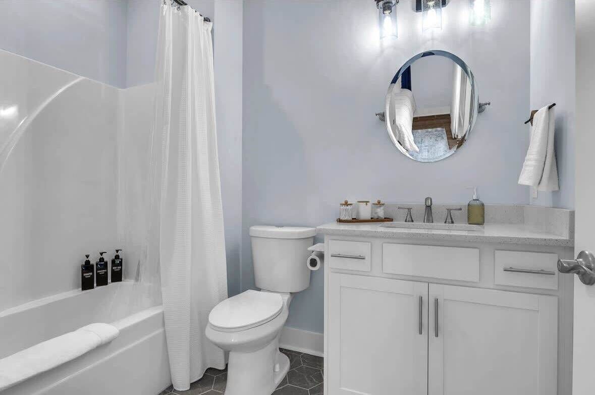 A bathroom with a bathtub, toilet, and vanity with a mirror.