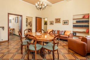 Un coin repas avec une table et des chaises en bois, un canapé et une bibliothèque.